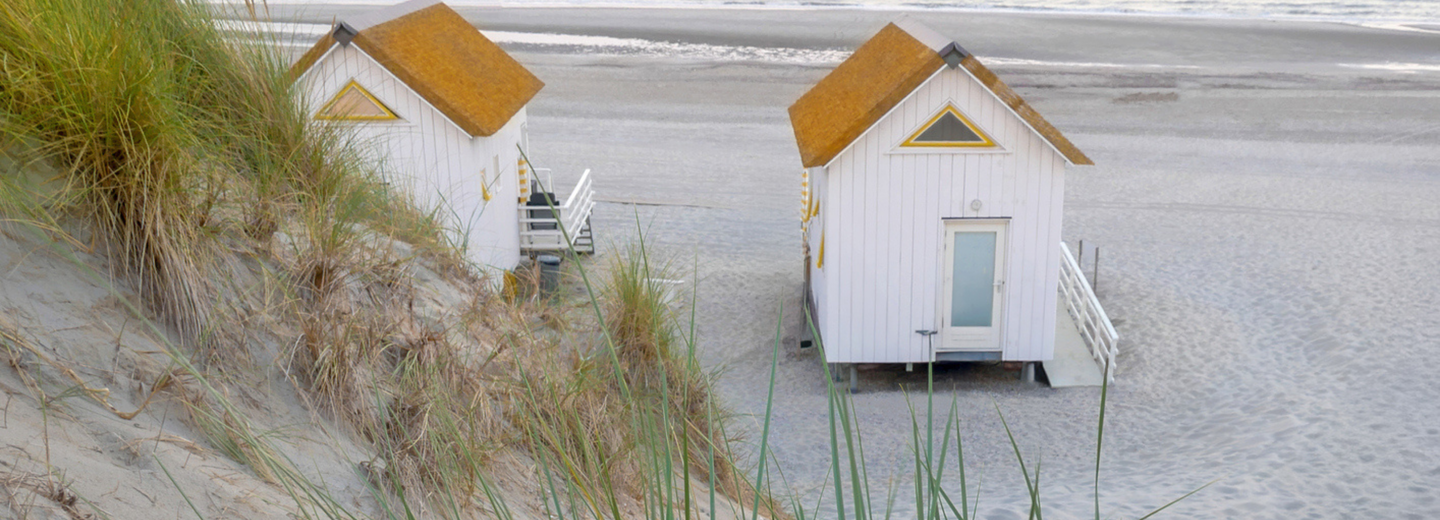 Kleine Häuser, die auf einem Sandstrand stehen. 