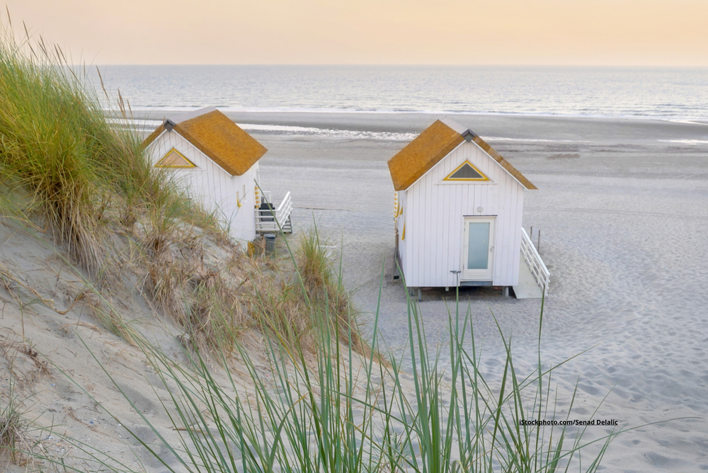 Kleine Häuser, die auf einem Sandstrand stehen. 