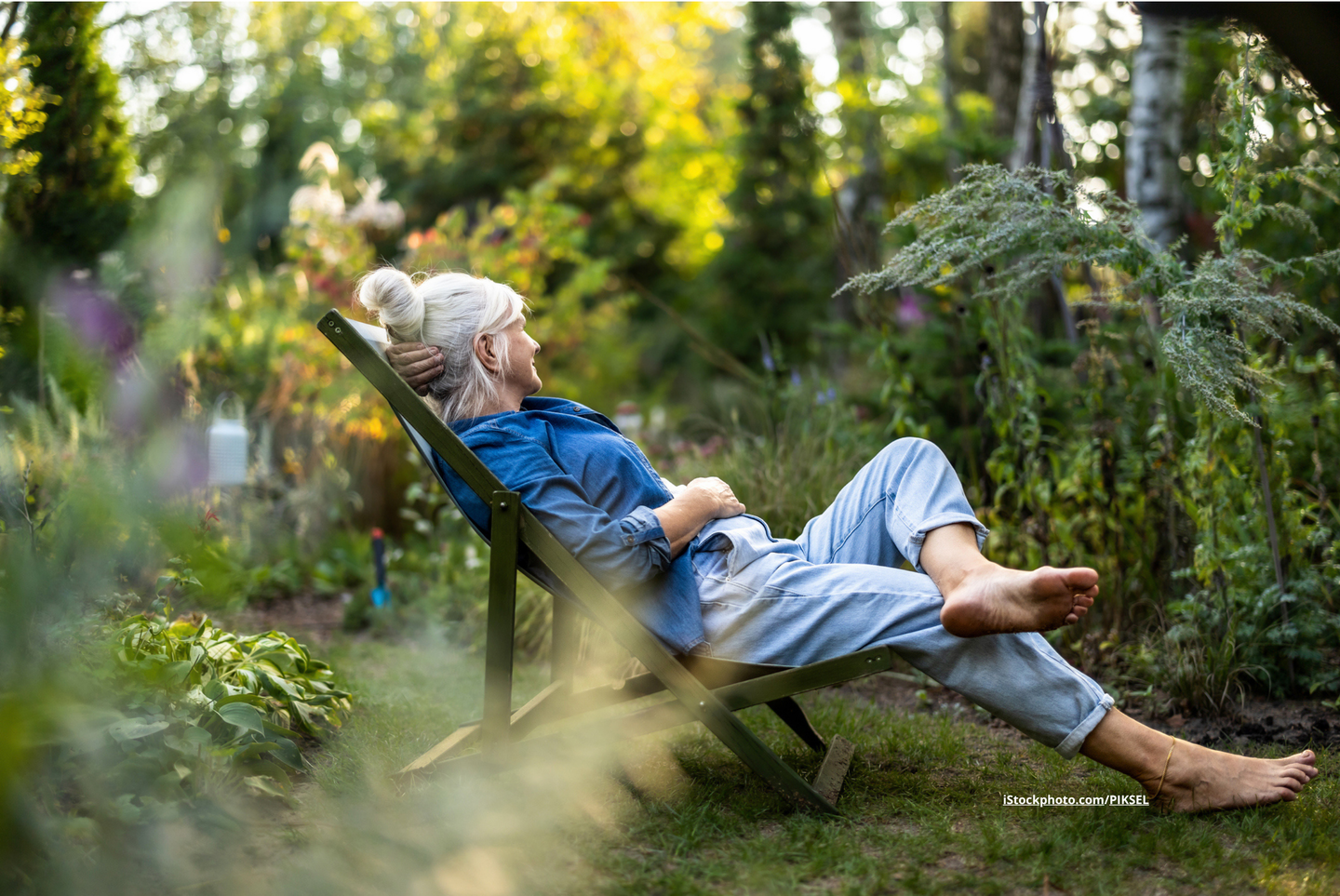 Eine Frau, die in einem Garten auf einem Liegestuhl sitzt. 
