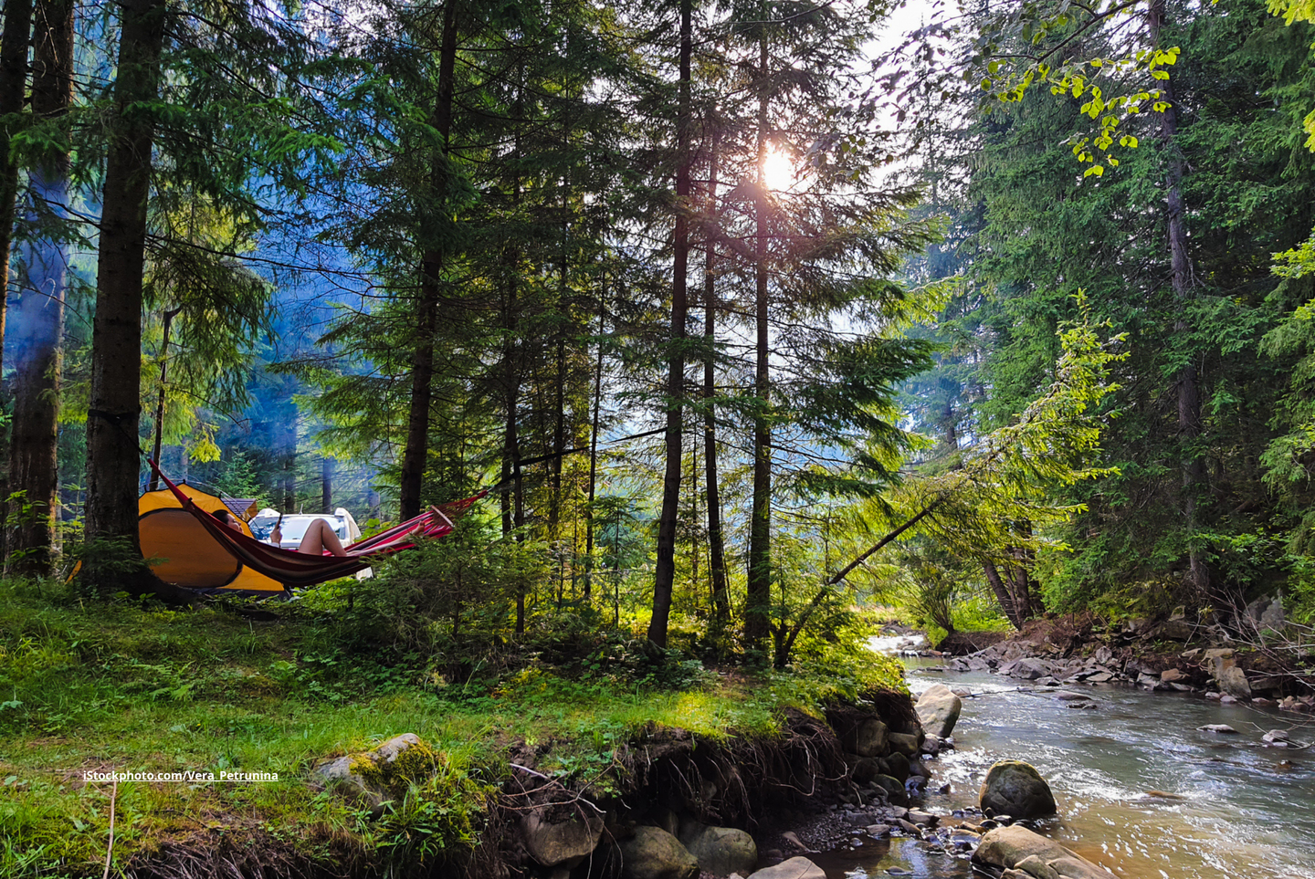 Eine Frau, die sich auf einer Hängematte auf einem Campingplatz im Wald ausruht