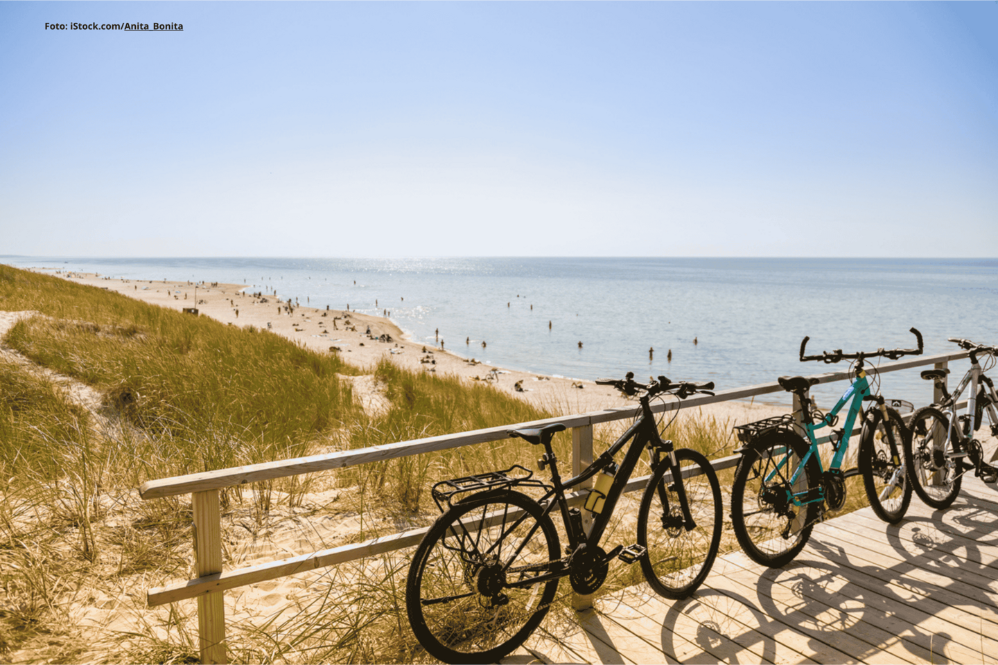 Das Foto zeigt drei Fahrräder am Geländer einer Brücke an einem Strand an der Ostsee bei gutem Wetter.