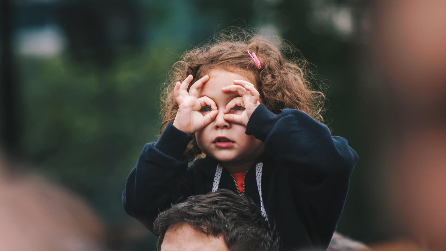 Ein Kind imitiert ein Fernglas mit den Händen.