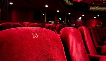 Das Foto zeigt einen imposanten Theatersaal mit roten Sitzen aus Samt.