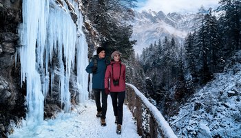 Das Foto zeigt zwei Personen bei einer Winterwanderung mit dem Fernglas.