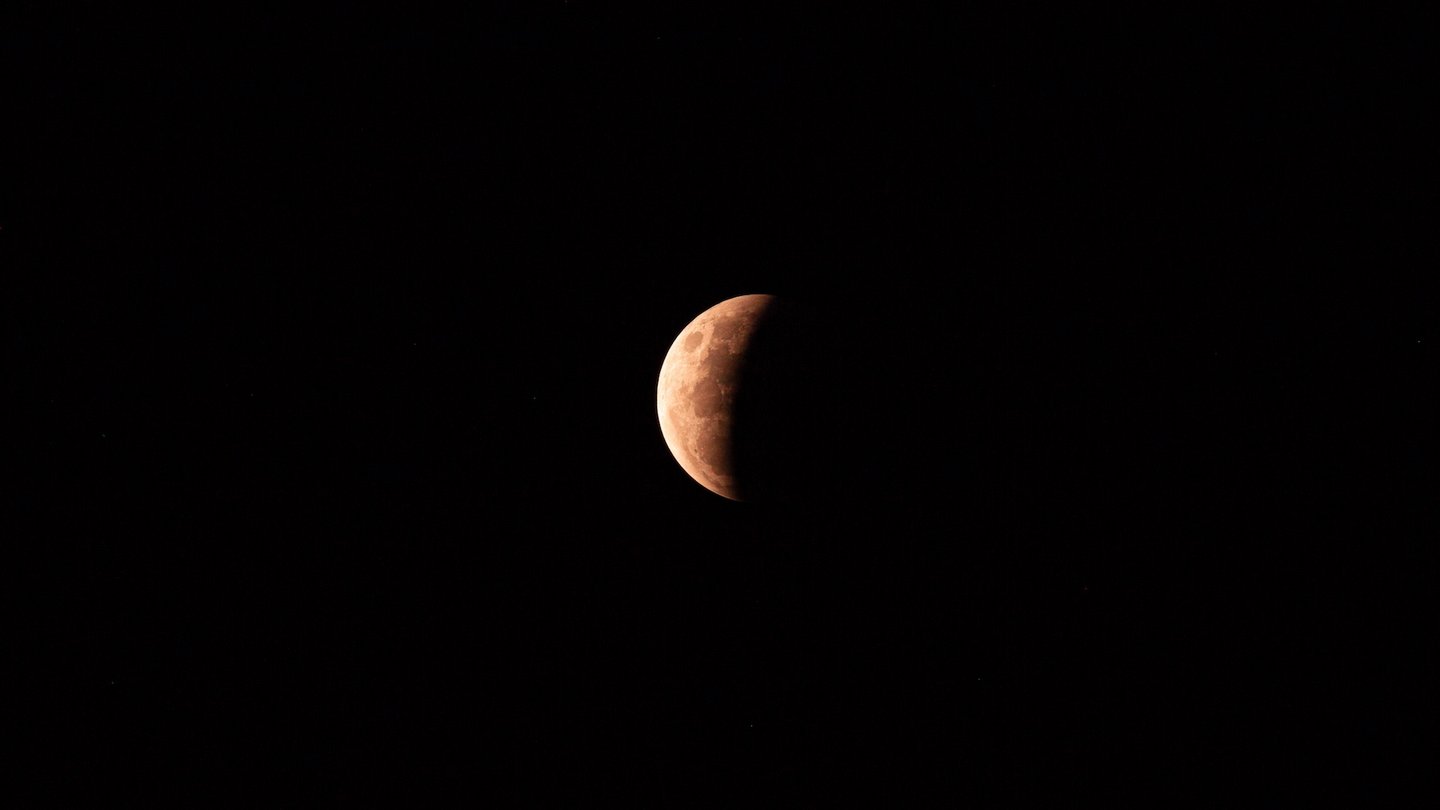 Das Bild zeigt eine partielle Mondfinsternis vor dem schwarzen Himmel.