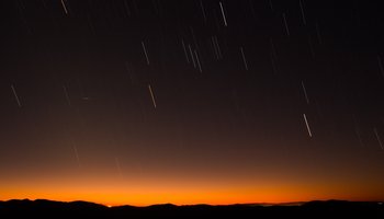 Das Foto zeigt einen Meteorschauer vor einem Himmel bei Sonnenuntergang.