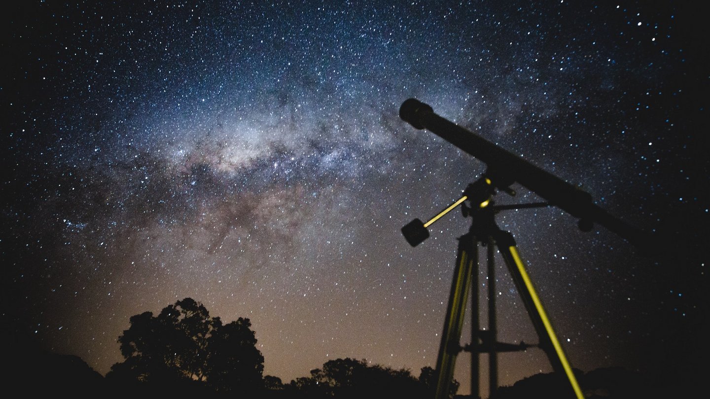 Ein Teleskop vor einem nächtlichen Sternenhimmel.