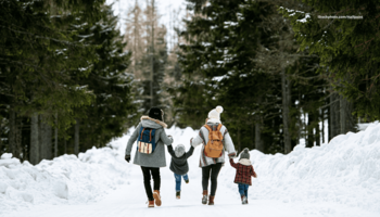 Das Foto zeigt eine Familie bei einem winterlichen Ausflug im verschneiten Wald.