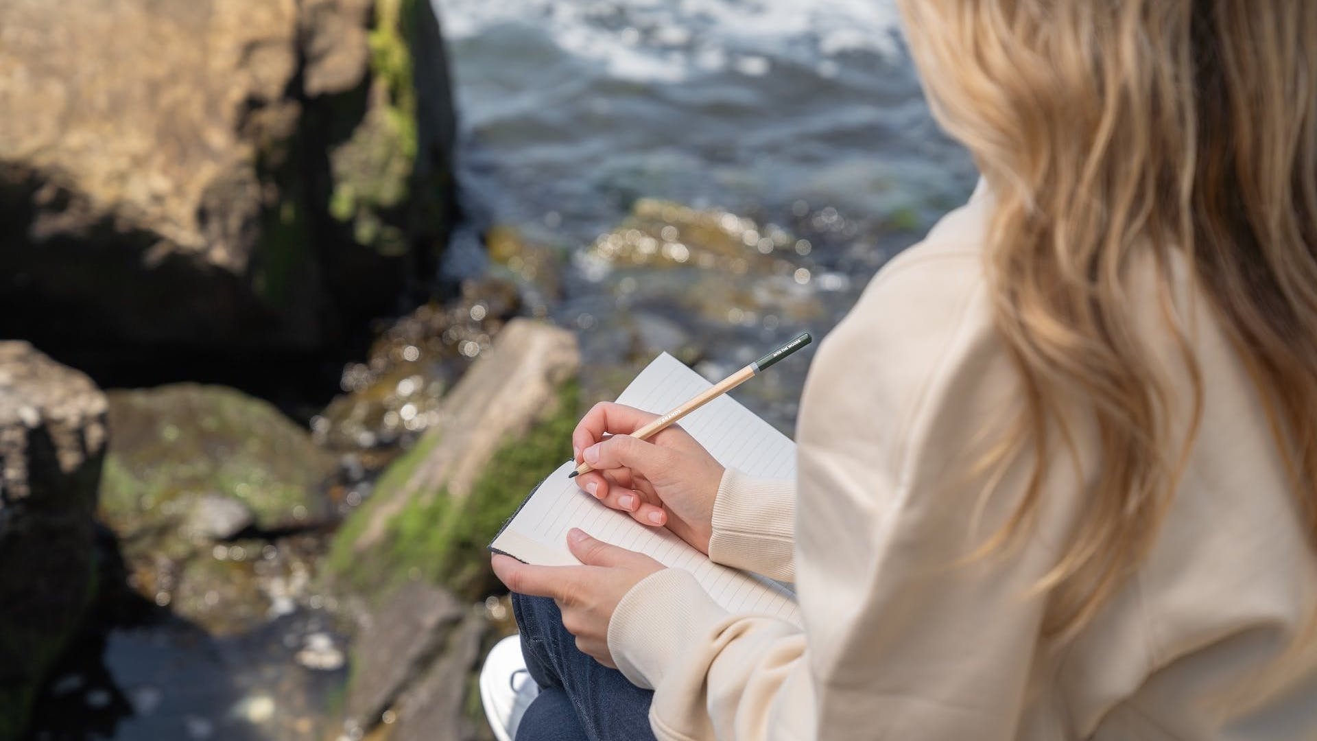 Das Foto zeigt eine Frau, die in der Natur Journaling betreibt.