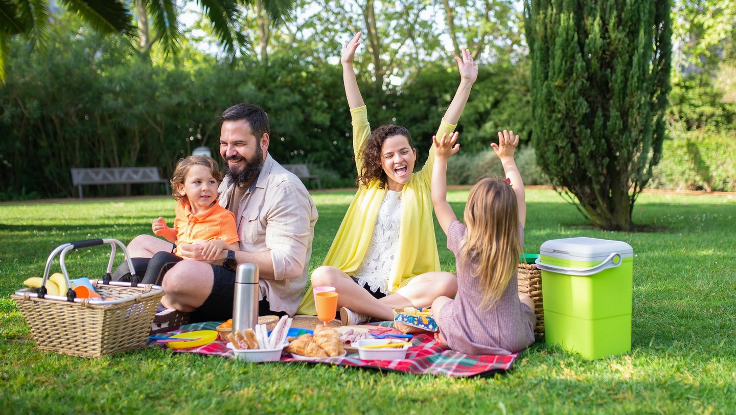 Das Foto zeigt eine Familie beim Picknick.