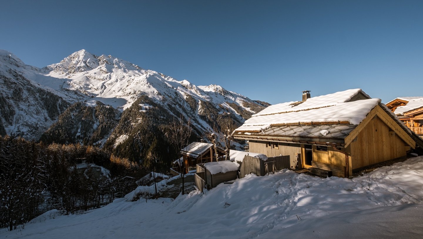 Das Foto zeigt eine Berghütte in den Alpen bei Schnee und Sonne.