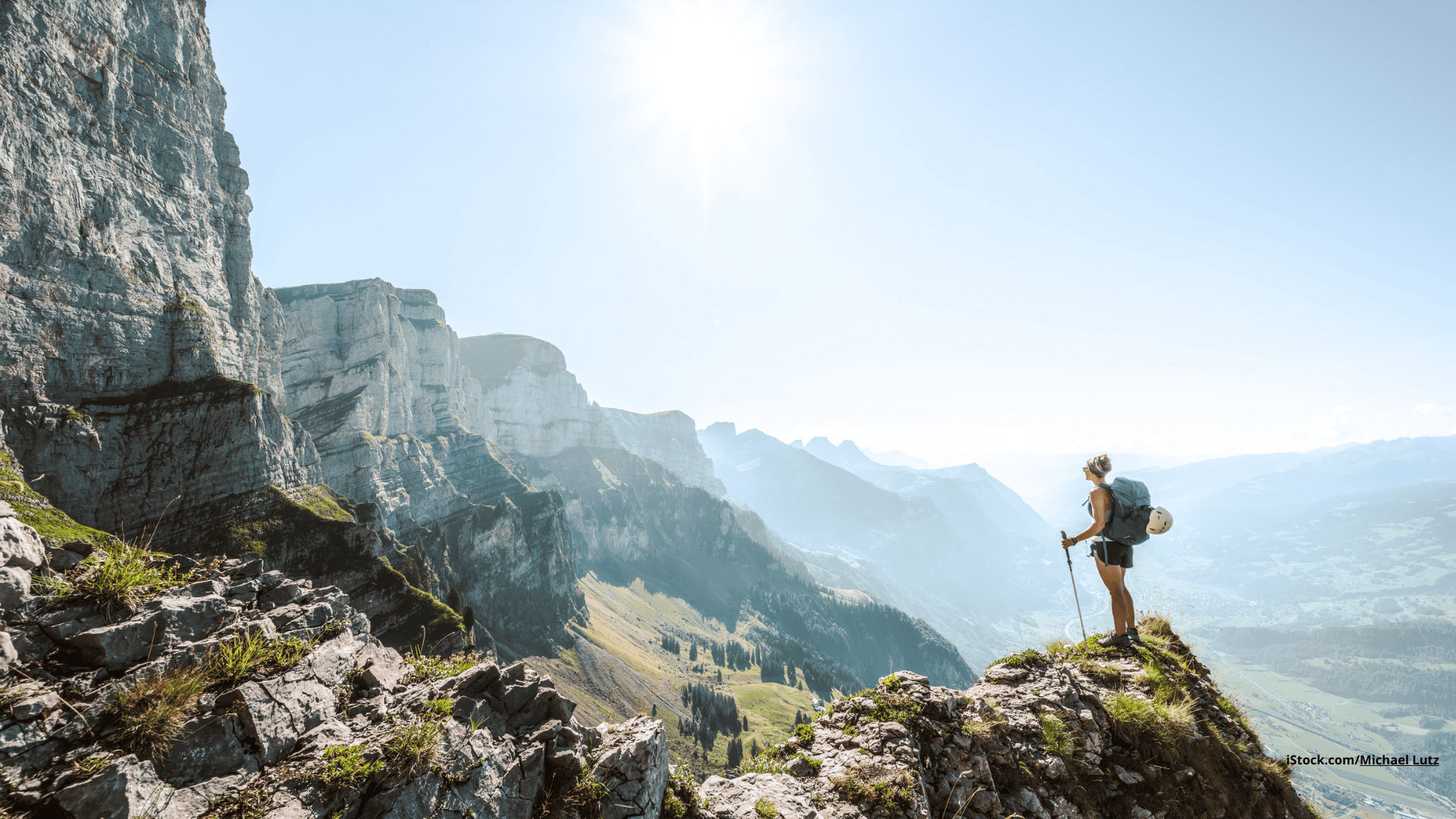 Das Foto zeigt eine Sportlerin auf einem Berg stehend bei Sonne und schöner Aussicht.