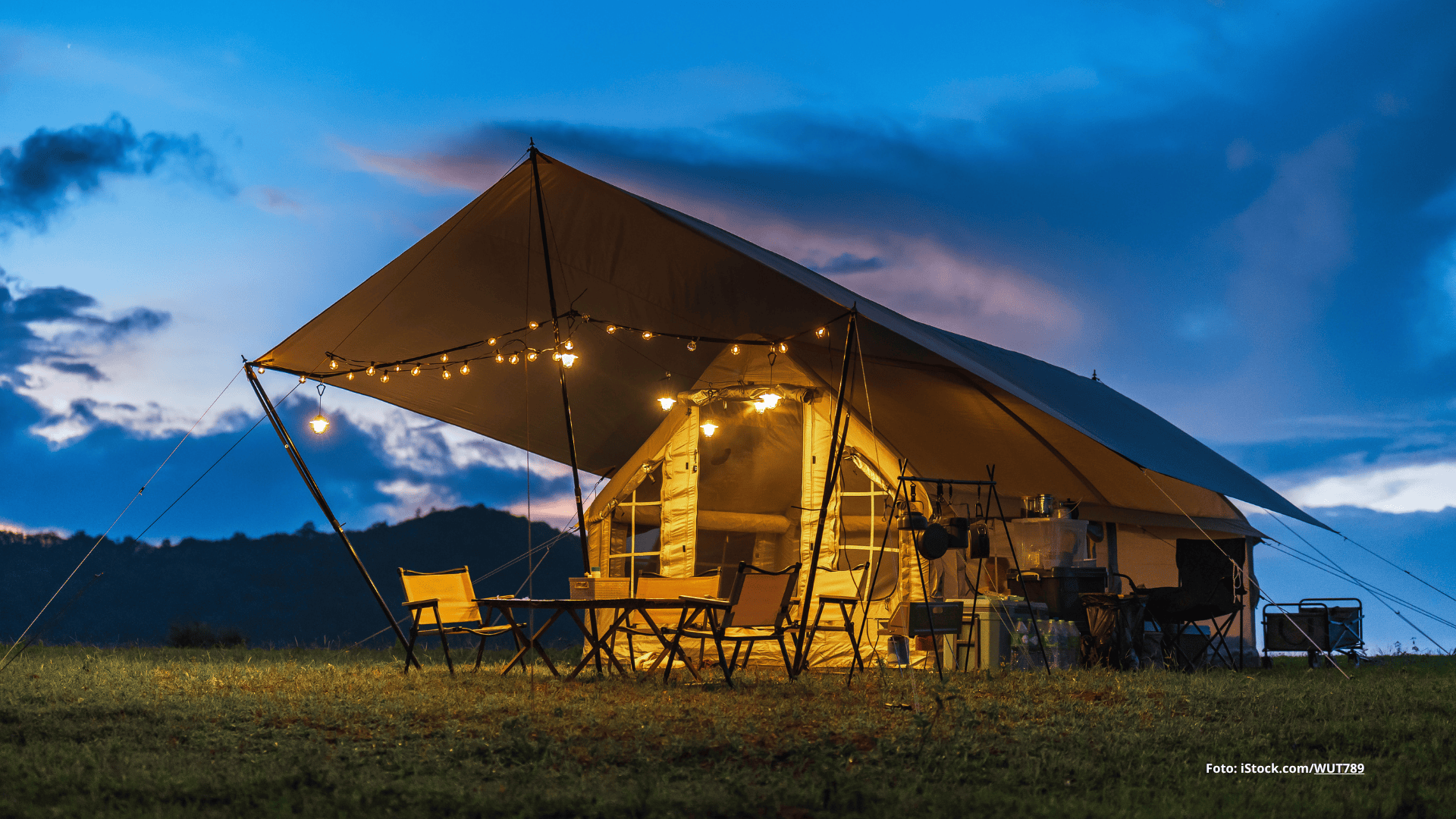 Das Foto zeigt ein Glamping-Zelt mit Lichterkette vor der untergehenden Sonne.