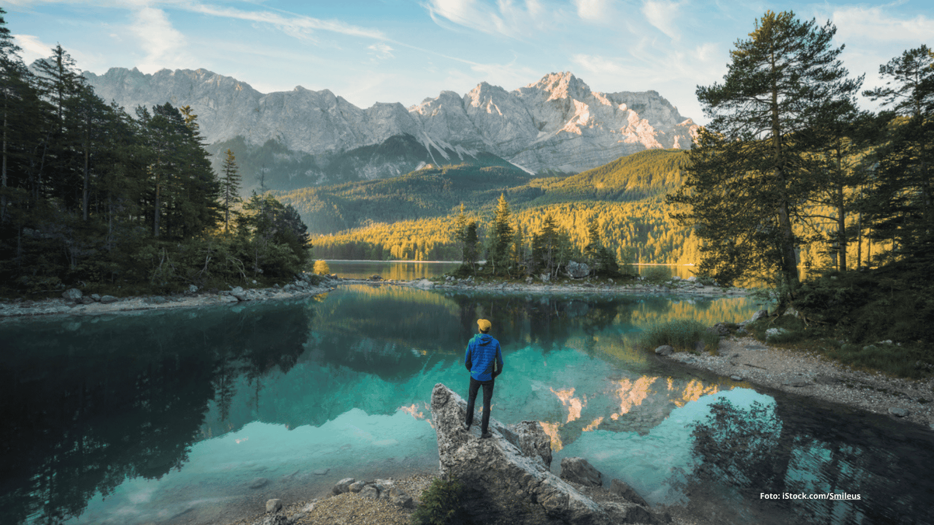 Das Foto zeigt eine Person vor dem schönen, blauen Eibsee in Bayern stehend bei Sonnenschein.